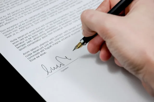 Free hand holding pen signing. Questions to ask a media buying agency before you sign: UK checklist